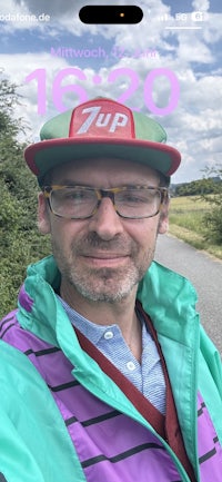 a man wearing a hat and glasses is taking a selfie